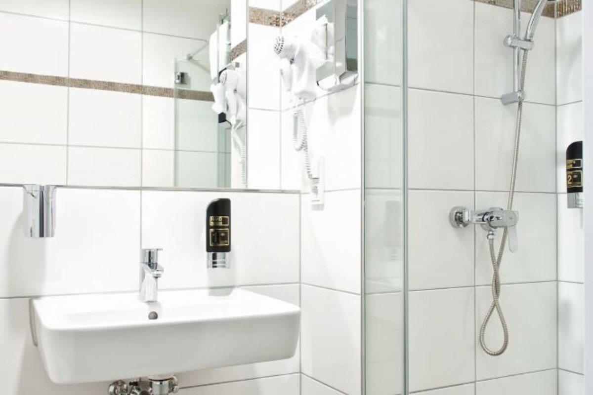 Un baño moderno con cabina de ducha de vidrio, un lavabo blanco con grifo y un espejo sobre el lavabo.