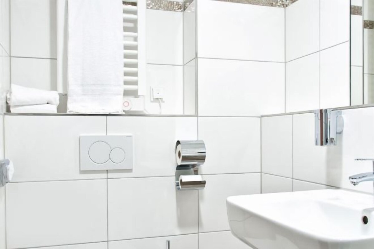 Ein modernes Badezimmer mit Waschbecken, Spiegel und Handtuchhalter.