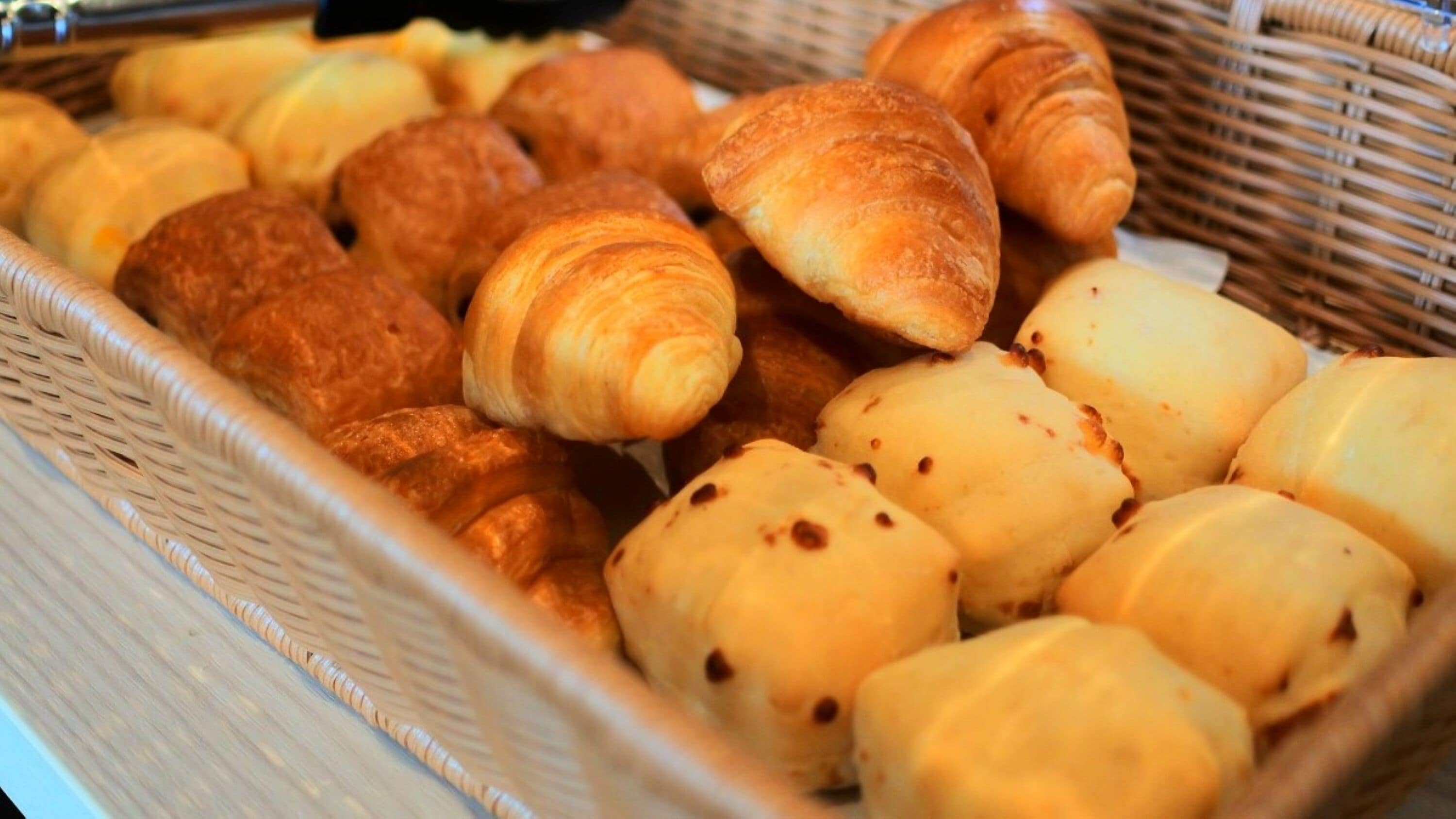 Un panier rempli de diverses viennoiseries, notamment des croissants et des petits pains.