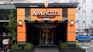 Exterior del APA Hotel con un diseño moderno, que destaca por su fachada naranja y detalles negros.