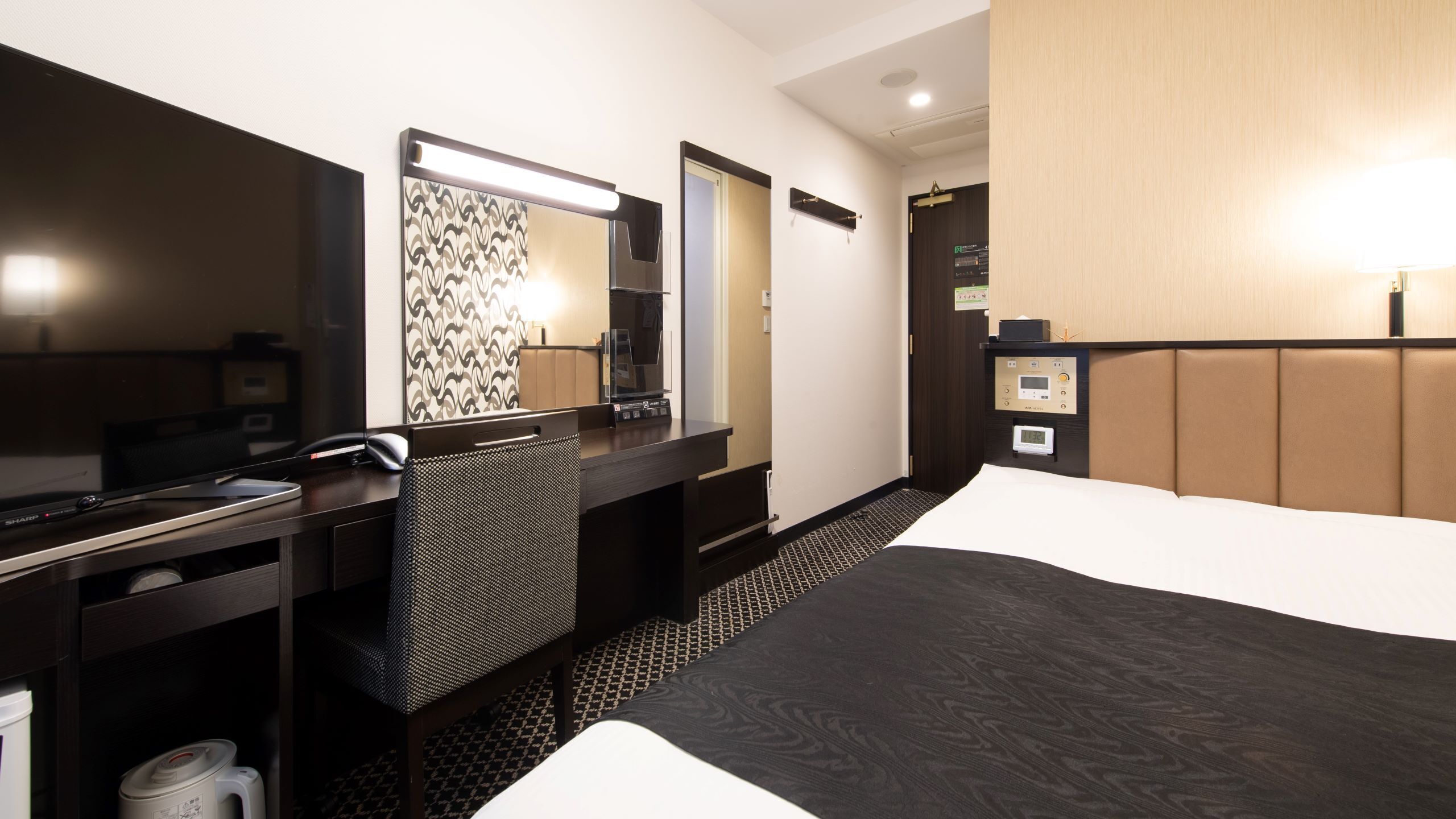 Een hotelkamer met een bureau, stoel, bed en spiegel.