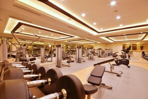 Un gimnasio moderno con diverso equipo de ejercicio, incluyendo mancuernas, cintas de correr y máquinas de pesas.
