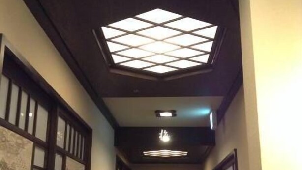 A hallway with a skylight, wooden doors, and a circular design on the wall. - Guest House Kuranomachi - Hostel (Tochigi)