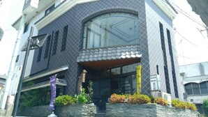 A hotel with a modern facade, a large arched window, and a small balcony. - Guest House Kuranomachi - Hostel (Tochigi)