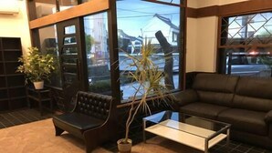 A modern interior with a leather sofa, a glass coffee table, and a potted plant. - Guest House Kuranomachi - Hostel (Tochigi)