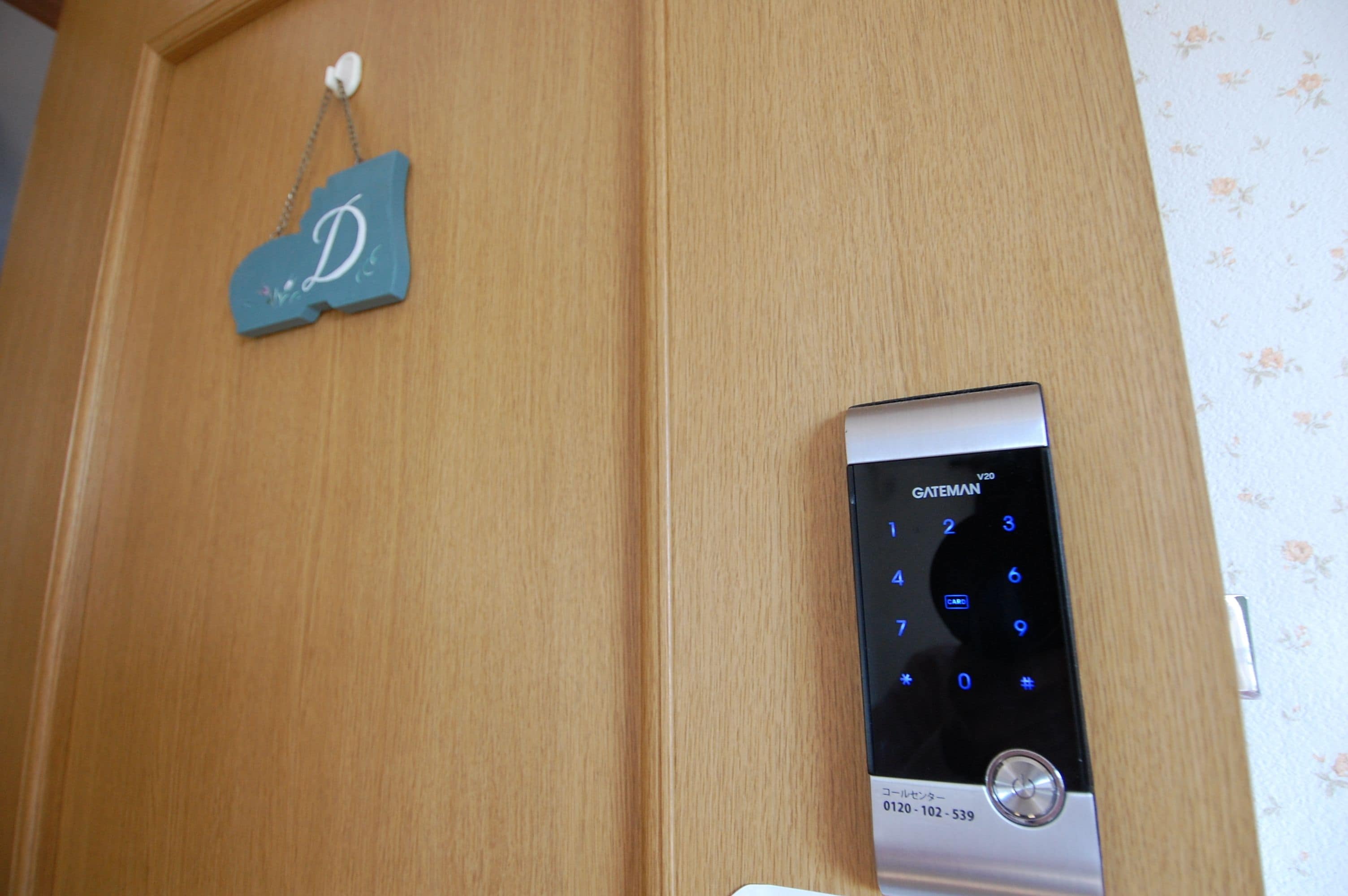 Una puerta de madera con un teclado digital y un pequeño letrero azul con la letra 'D'.