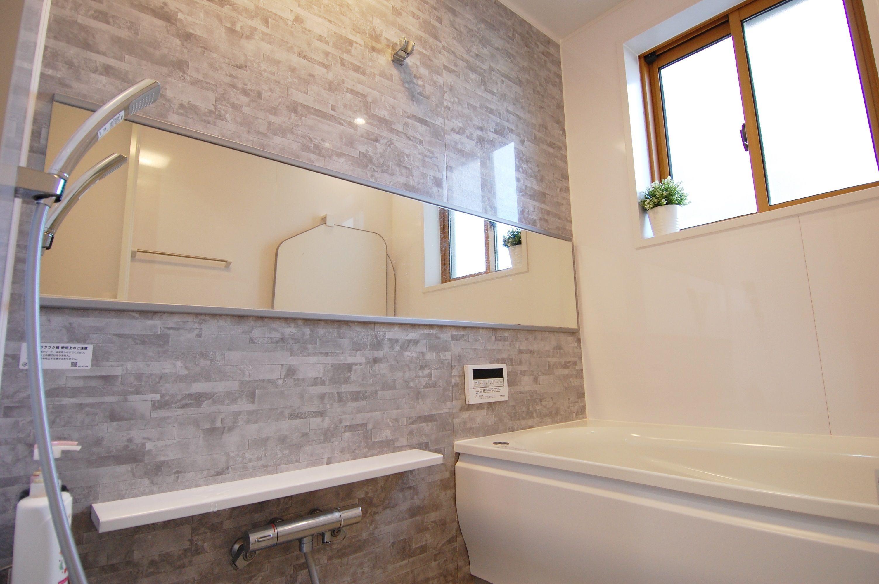 Un baño de diseño moderno, con ducha, bañera y una ventana con una planta.