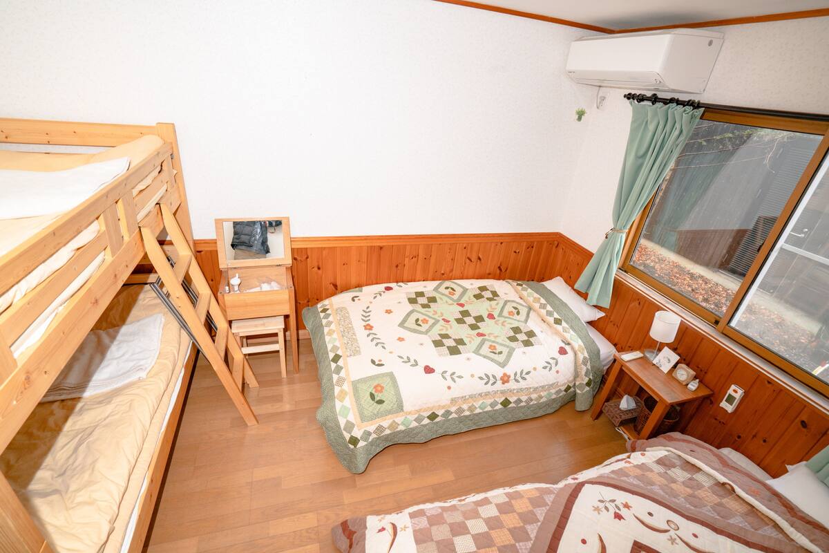 A compact room with a bunk bed, a desk, and a large window with curtains.