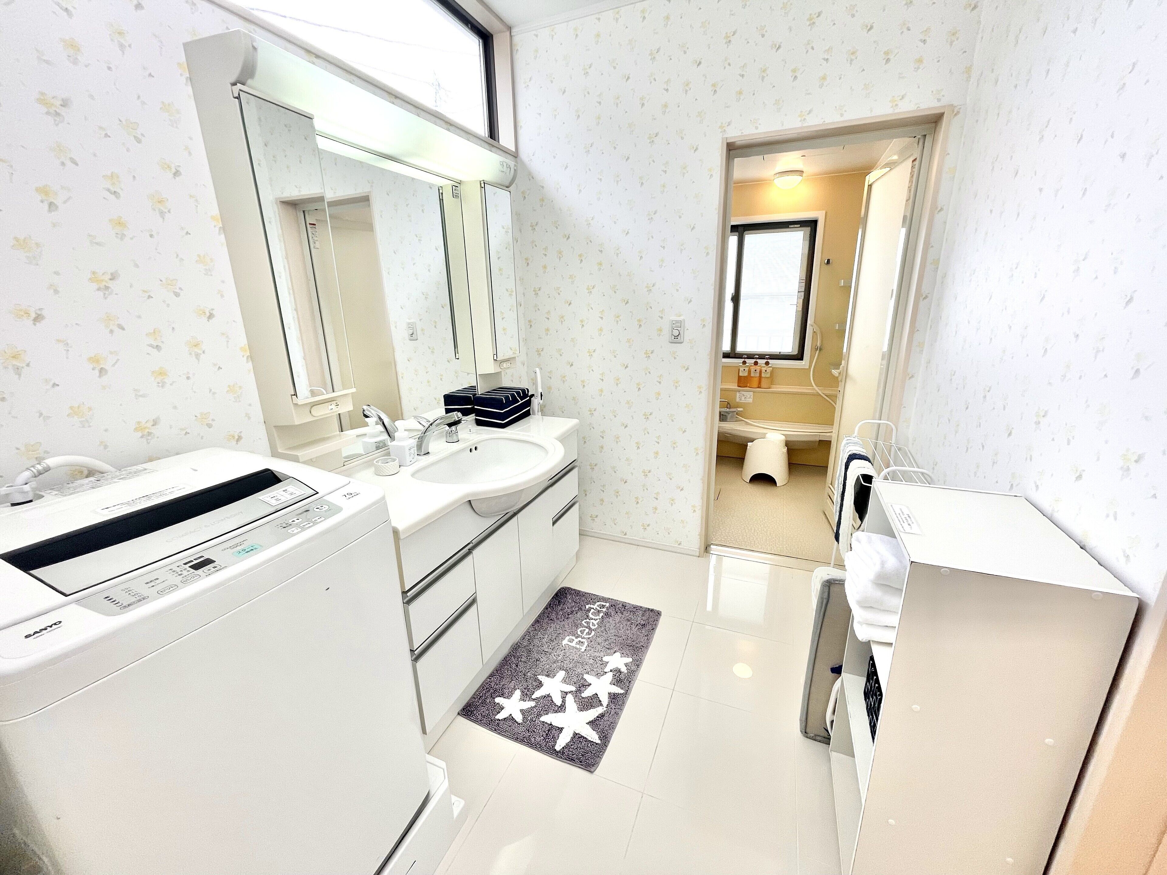 A modern bathroom with a large mirror, a sink, a toilet, and a washing machine.