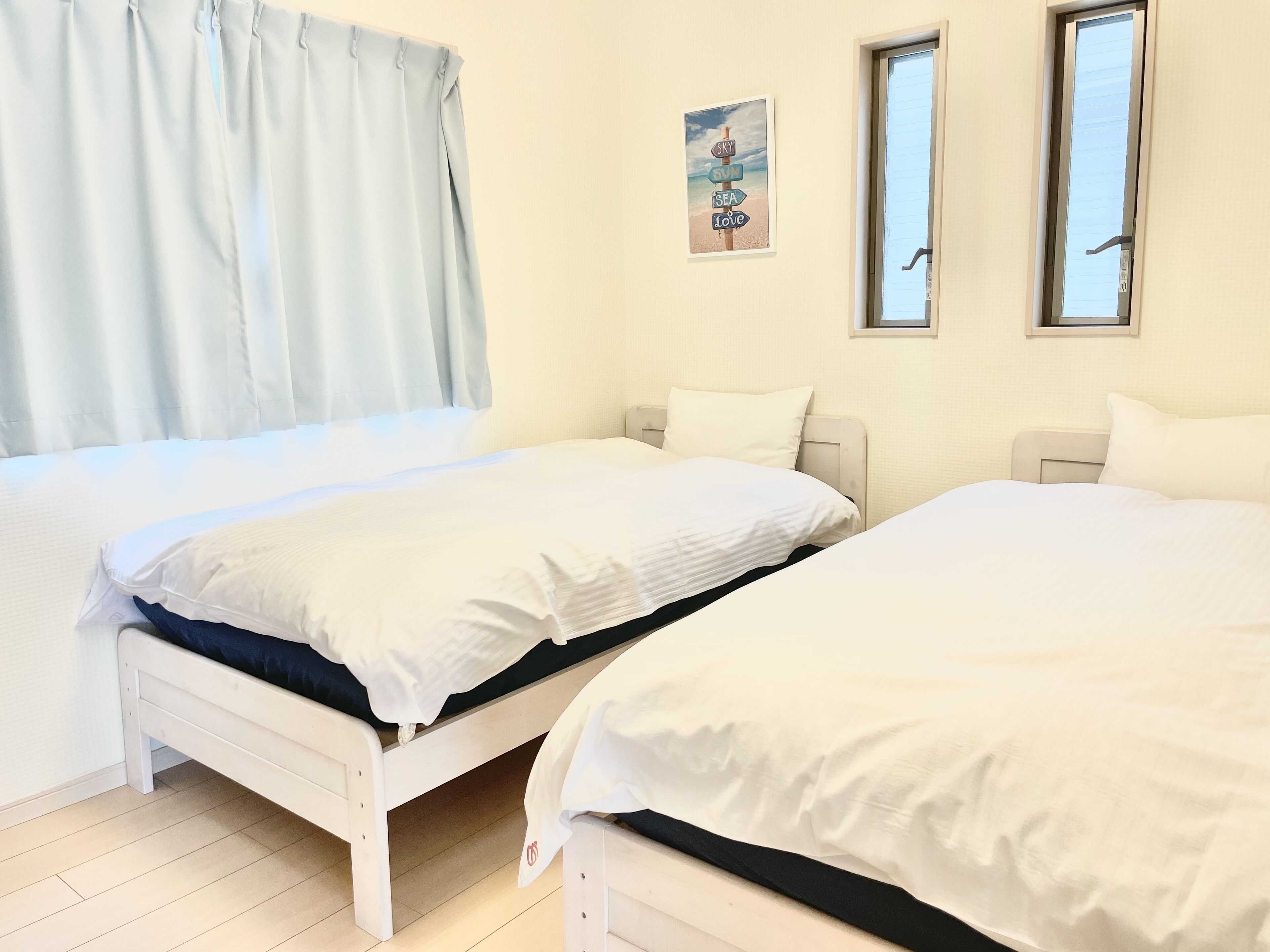 Ein Schlafzimmer mit zwei Betten, einem Fenster und einem Wandbild.