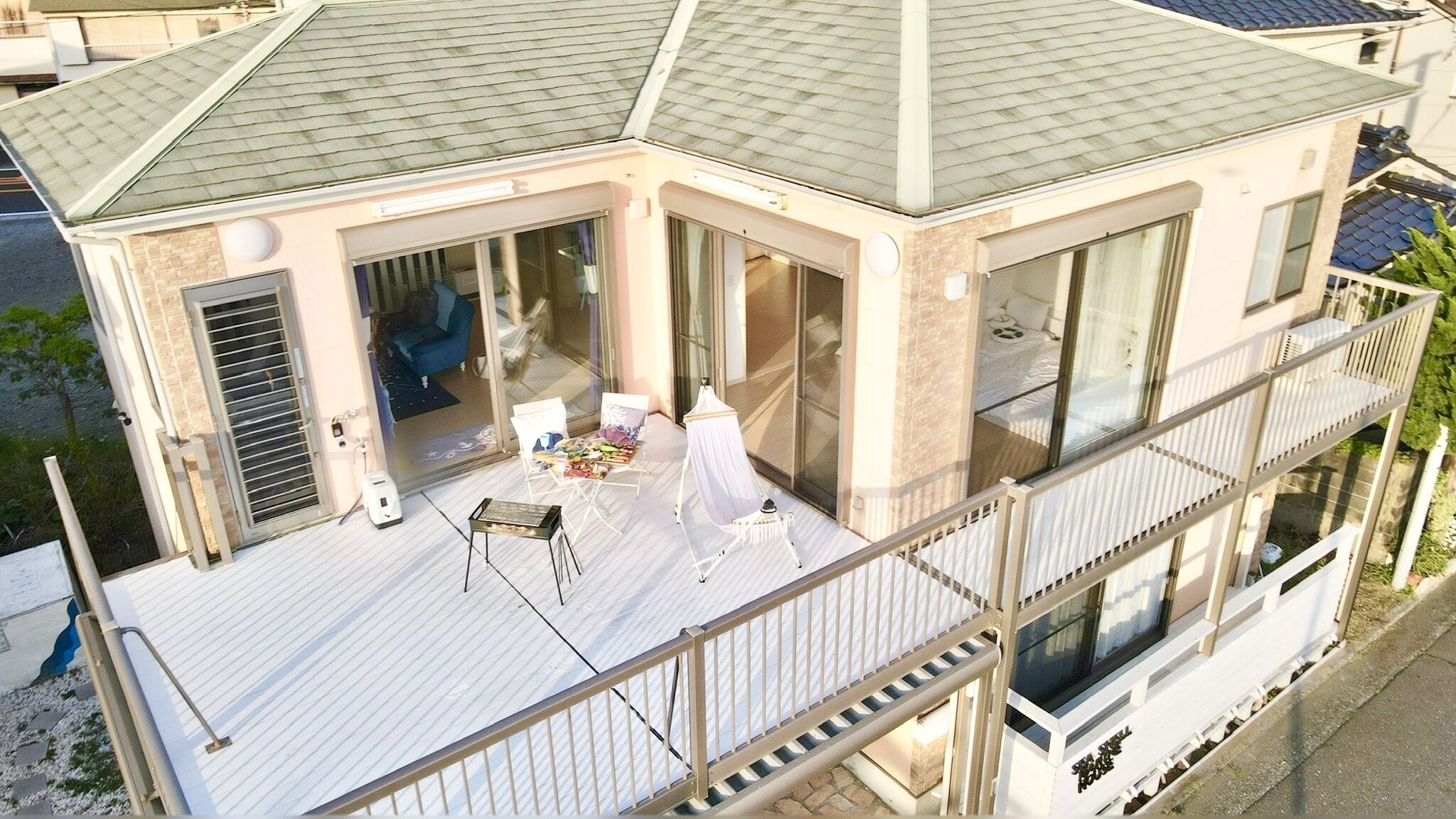 Ein modernes Haus mit Balkon, großen Fenstern und einer überdachten Terrasse.