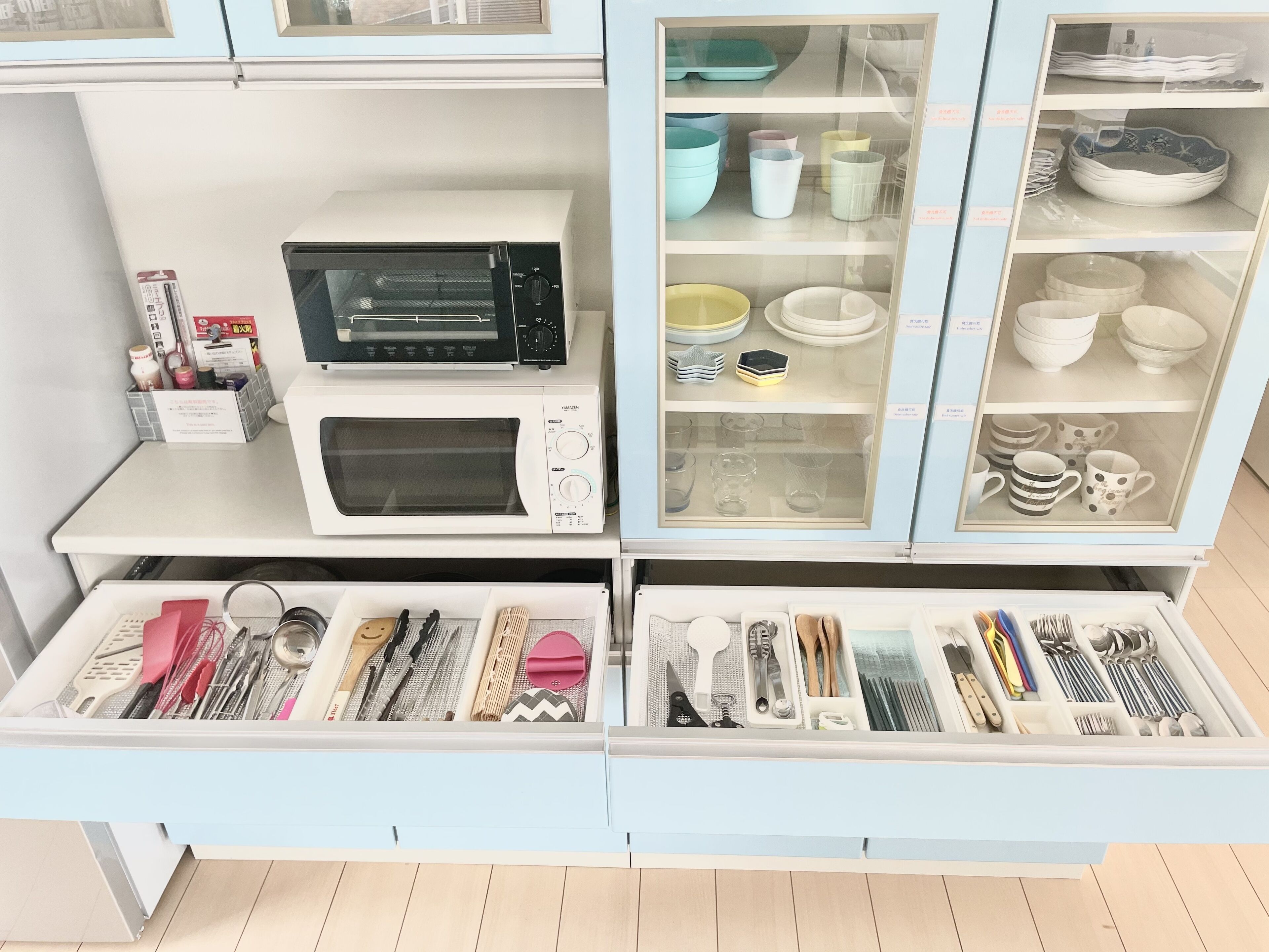 A kitchen with a microwave, oven, and various utensils and cookware.