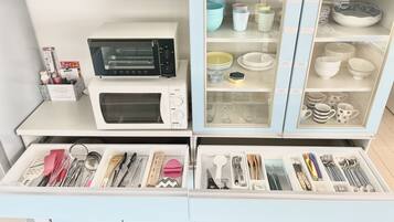 A kitchen with a microwave, oven, and various utensils and cookware.