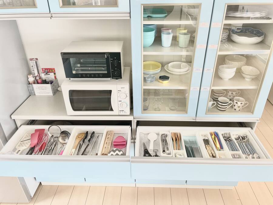 A kitchen with a microwave, oven, and various utensils and cookware.