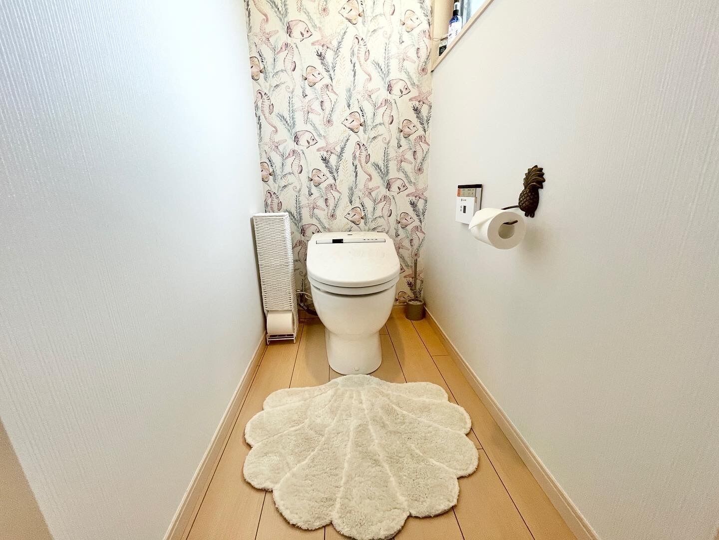 A narrow bathroom with a toilet, a radiator, and a patterned wallpaper.
