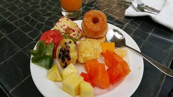 A plate with various fruits and a glass of orange juice on a table.