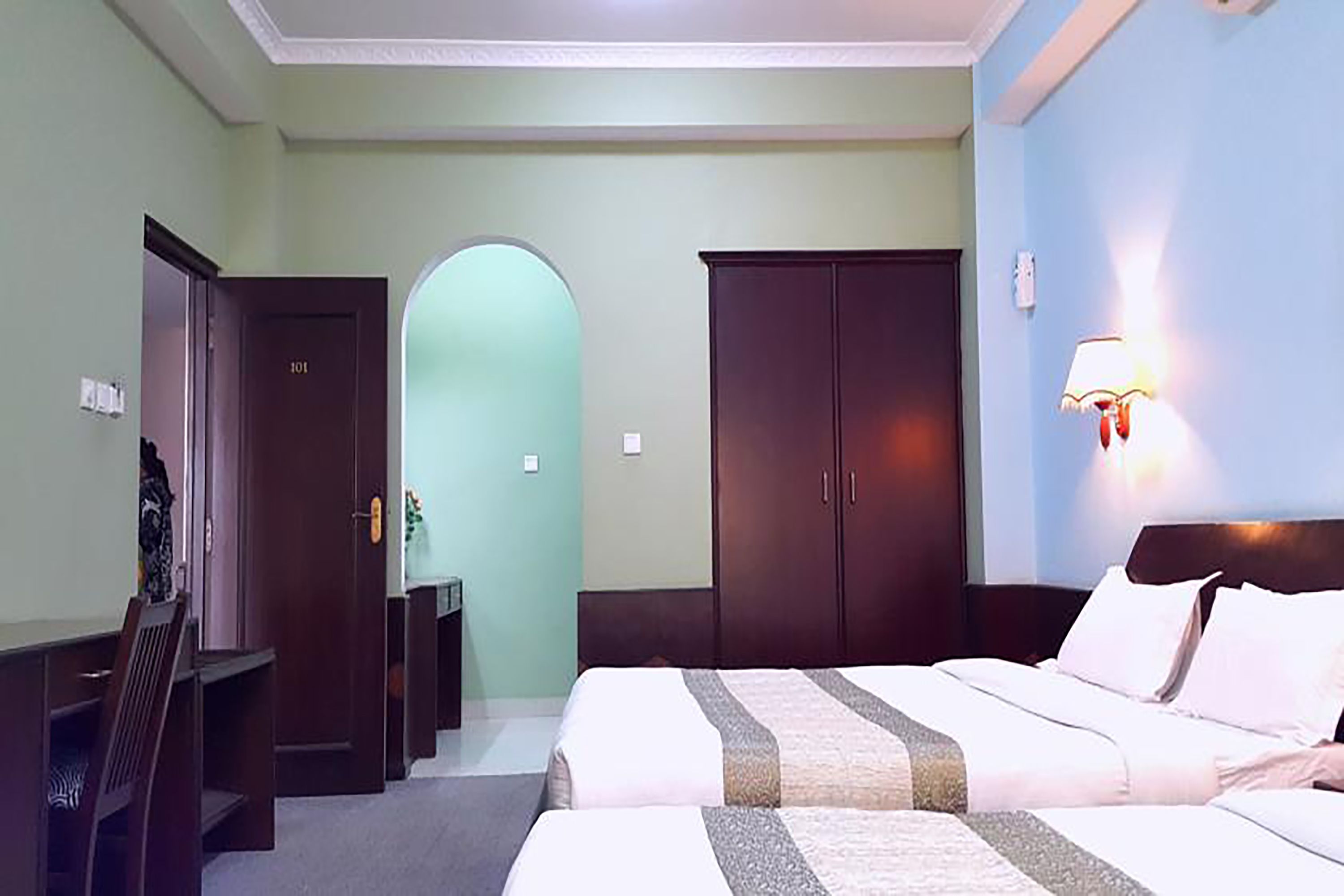 A hotel room with a bed, a desk, and a wardrobe.