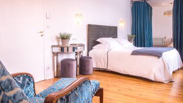A bedroom with a bed, bedside table, lamp, and a chair.