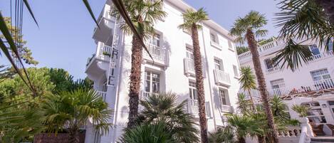 A multi-story hotel with balconies, palm trees, and a staircase leading to an upper level.