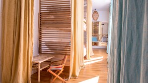 Una habitación con un banco de madera, una silla a rayas y una cama con almohada azul y blanca a rayas.