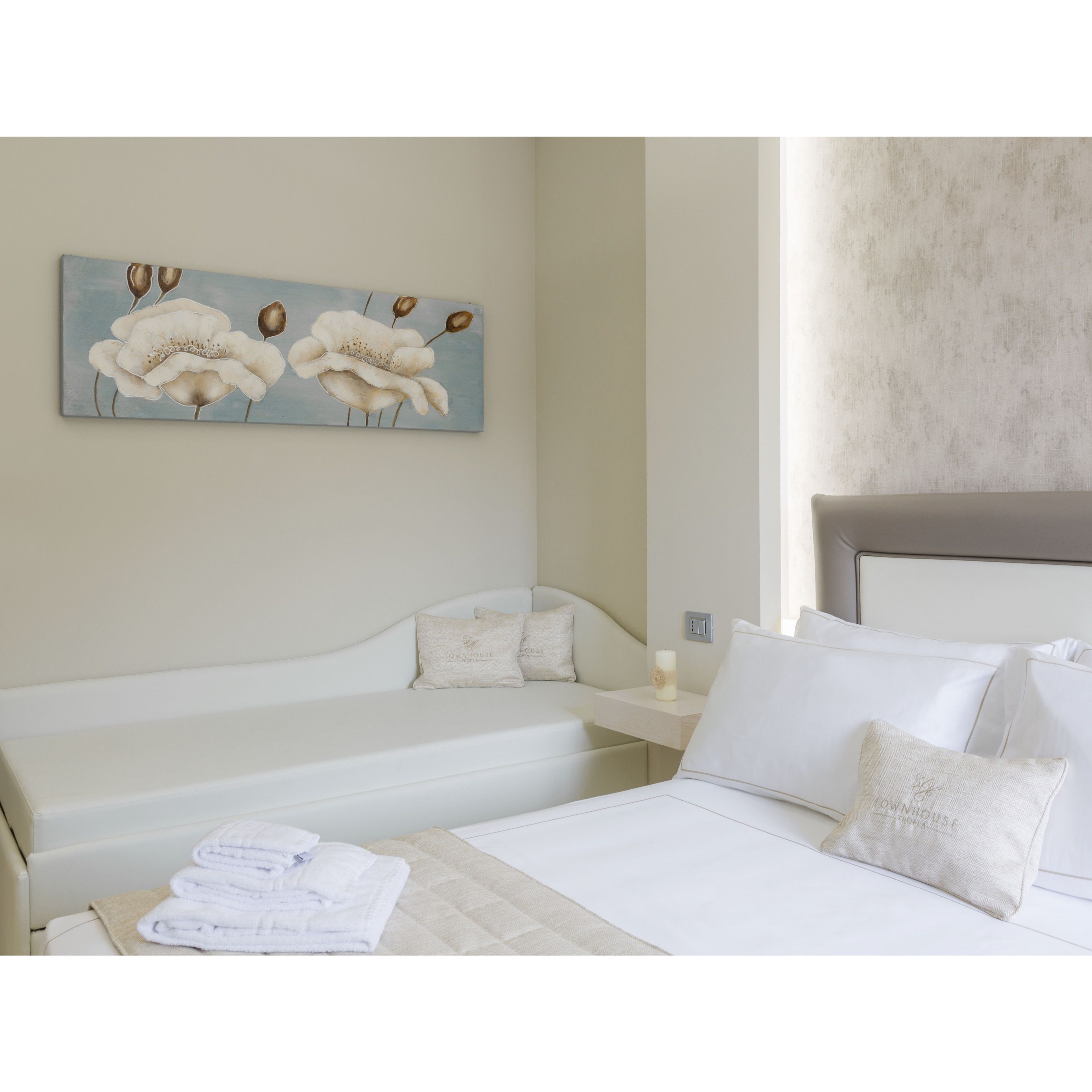 Una habitación de hotel con una cama, una mesita de noche y un cuadro de flores en la pared.