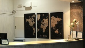 A reception desk with three world maps on the wall, a security camera, and a vase with flowers.