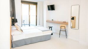Une chambre d’hôtel moderne équipée d’un lit, d’un bureau, d’une chaise, d’une télévision et d’un grand miroir.