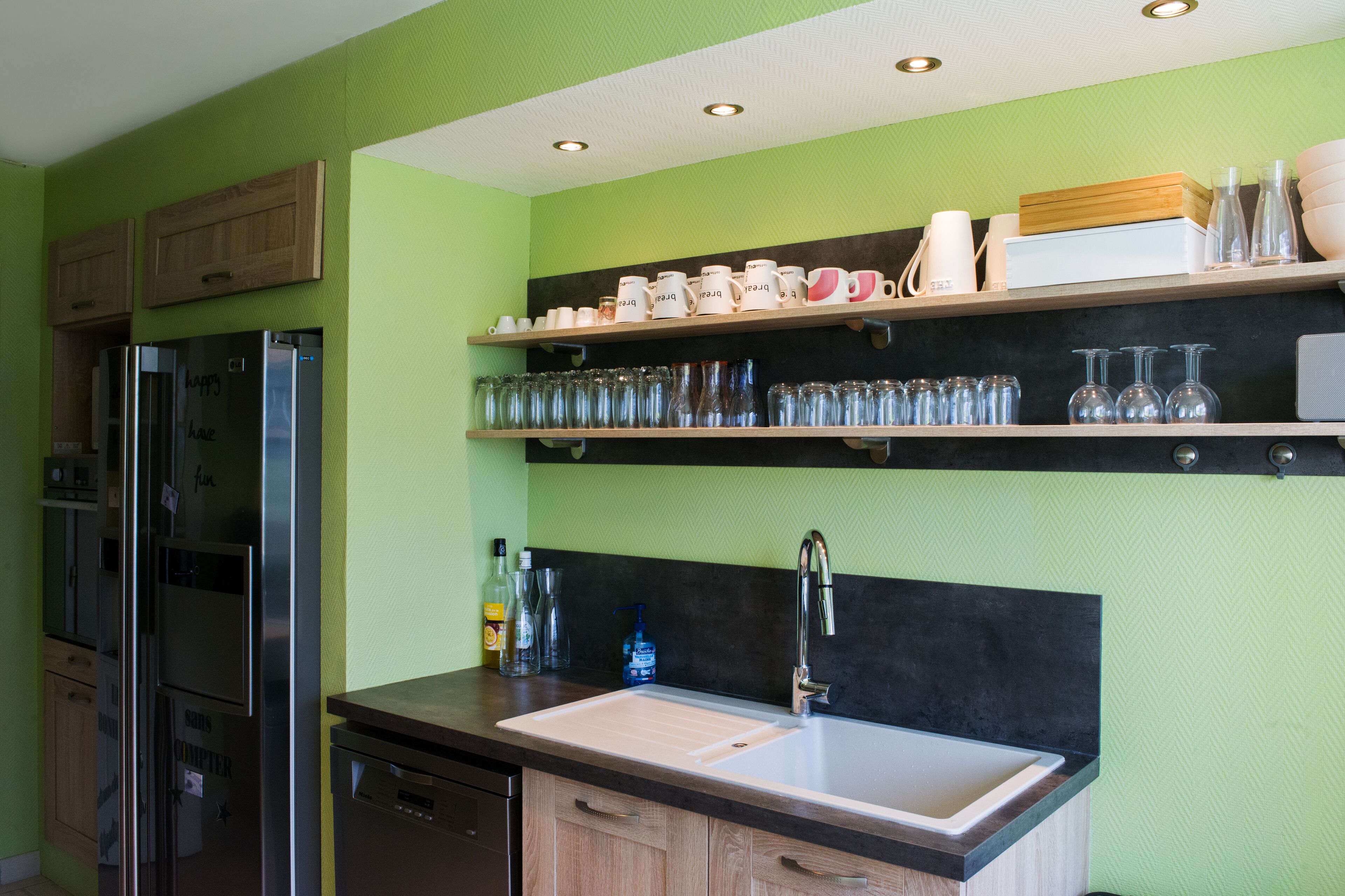 A modern kitchen with stainless steel appliances, a double sink, and wooden cabinets.