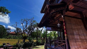 A wooden building with a balcony, surrounded by lush greenery and a clear blue sky. - Ganesha Ubud Inn (Ubud)