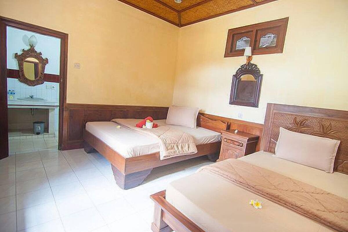 A hotel room with two single beds, a wooden headboard, a nightstand, and a mirror.