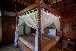 A four-poster bed with a canopy, wooden walls, and a small bedside table with a flower.