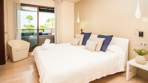 A bedroom with a large bed, a bedside table, a chair, and a view of the outdoors. - Medina Luxury Penthouse (Marbella)