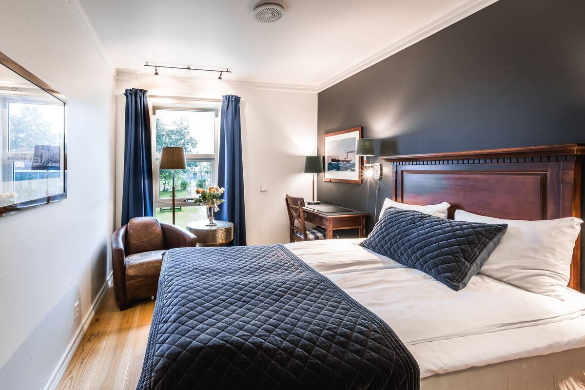 Ein Hotelzimmer mit einem Bett, einem Schreibtisch, einem Stuhl und einem Fenster mit Vorhängen.