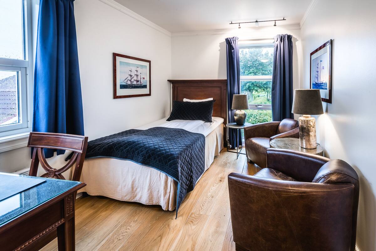 Ein Hotelzimmer mit Bett, Schreibtisch, Stuhl und Lampe.