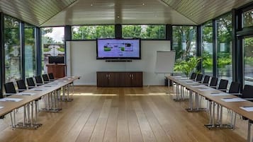 A conference room with a long table, chairs, a television screen, and a whiteboard.