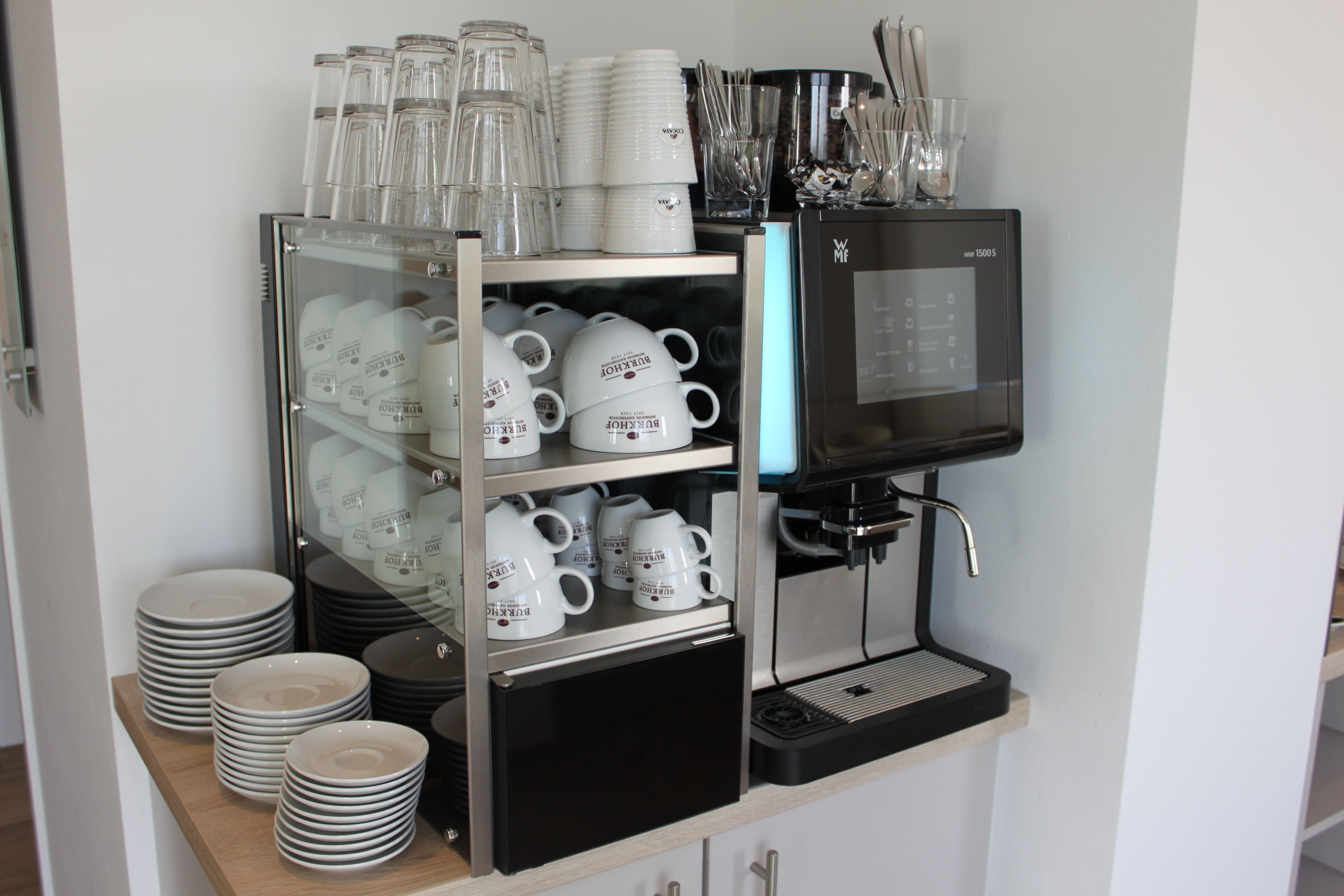 Un coin café équipé d’une machine à café, de tasses et d’assiettes.