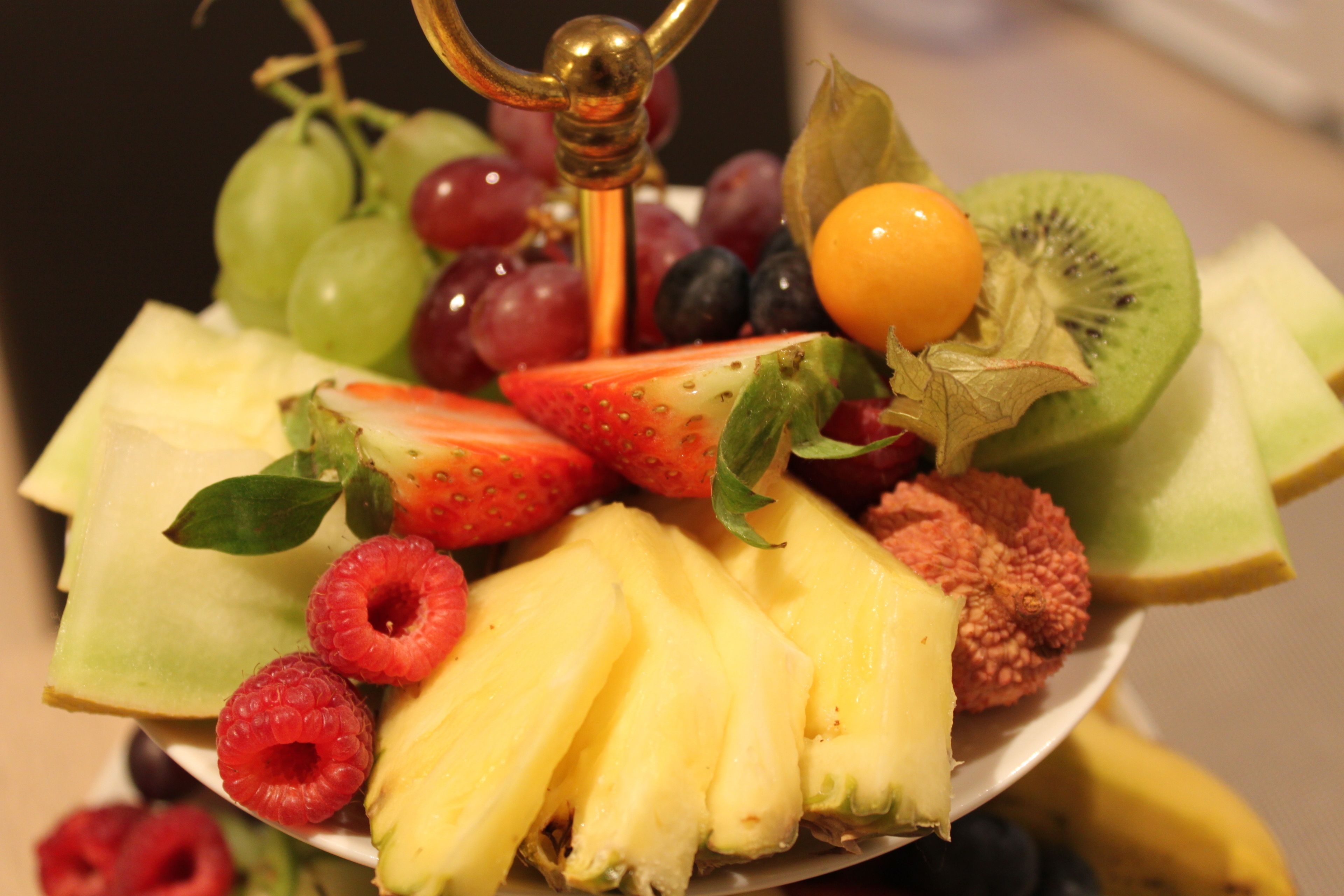 Eine Obstplatte mit verschiedenen Früchten, darunter Trauben, Erdbeeren, Kiwis, Ananas und Himbeeren.
