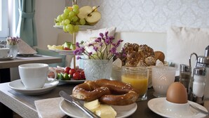 Ein Frühstückstisch mit Tellern voller Speisen, einer Tasse, einem Messer und einer Schüssel Obst.