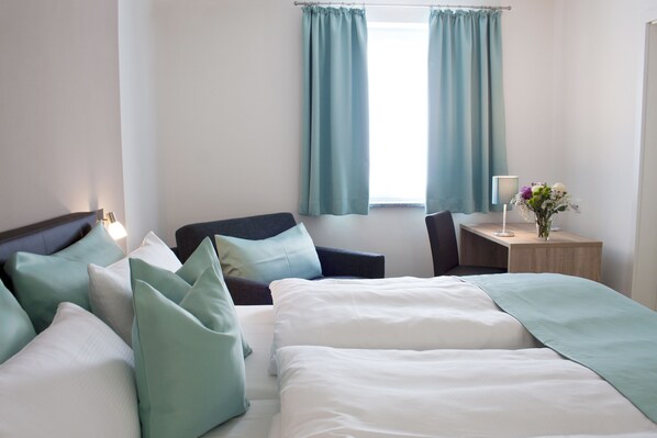 A hotel room with a bed, a chair, a desk, and a window with curtains. - Hotel Claro garni (Eitting)