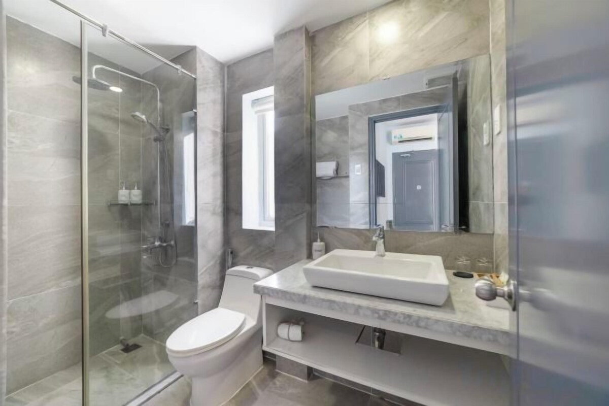 Un baño moderno con cabina de ducha de vidrio, un inodoro y un lavabo con un espejo grande.