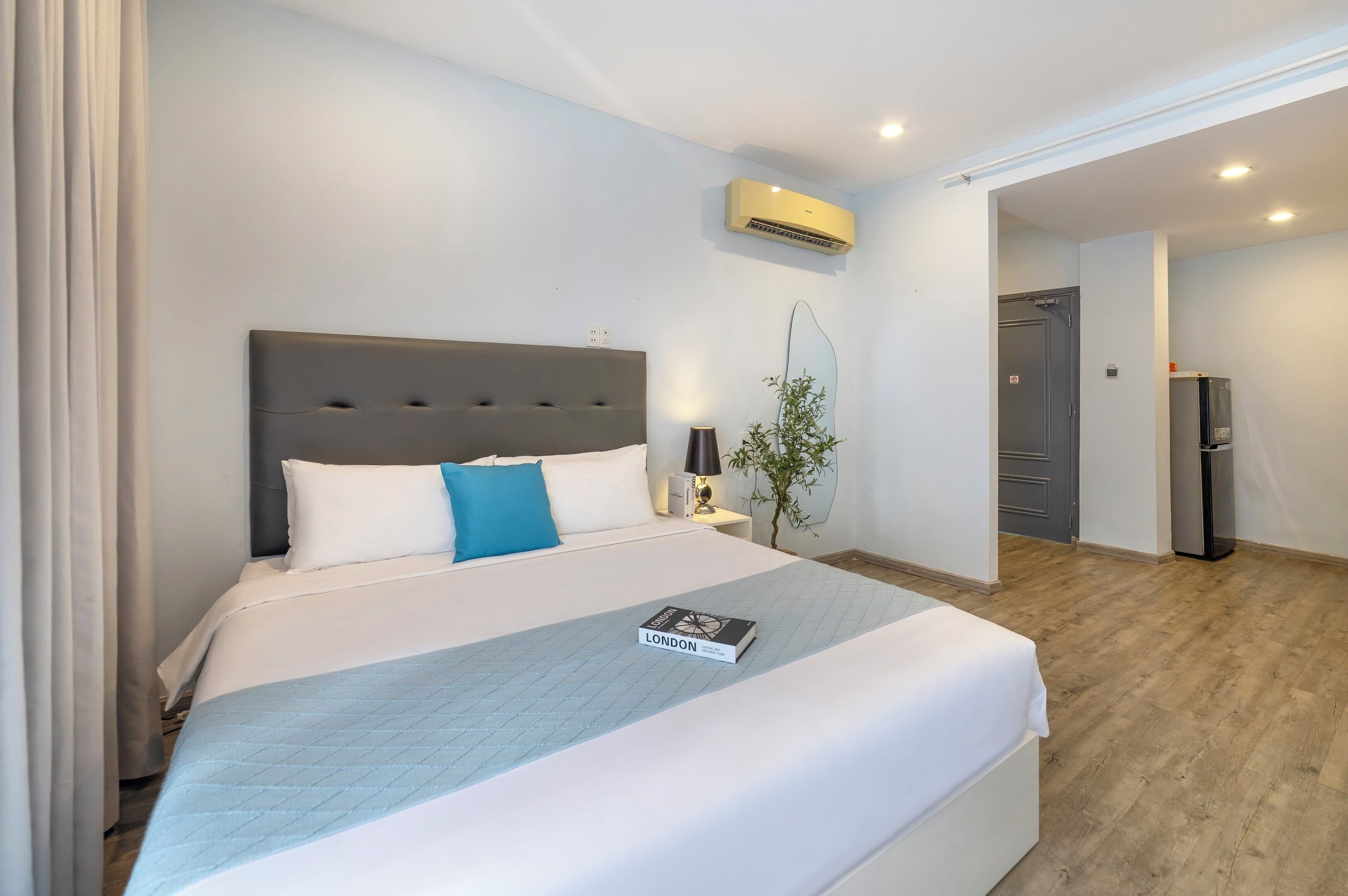 Une chambre d’hôtel avec un grand lit, une table de chevet, une lampe et une plante.