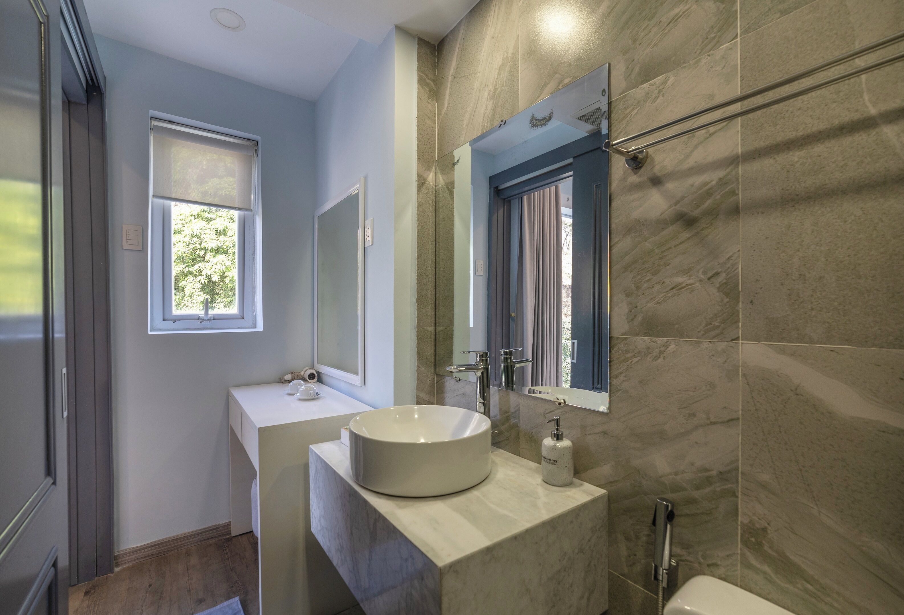 Un baño moderno con un lavamanos grande, un espejo y una ventana.