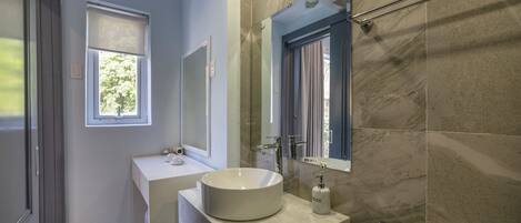 Un baño moderno con un lavamanos grande, un espejo y una ventana.