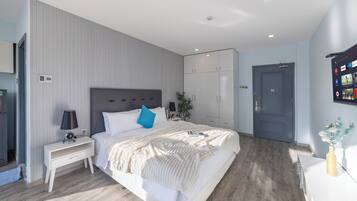 A modern bedroom with a large bed, a nightstand, a wardrobe, and a door.