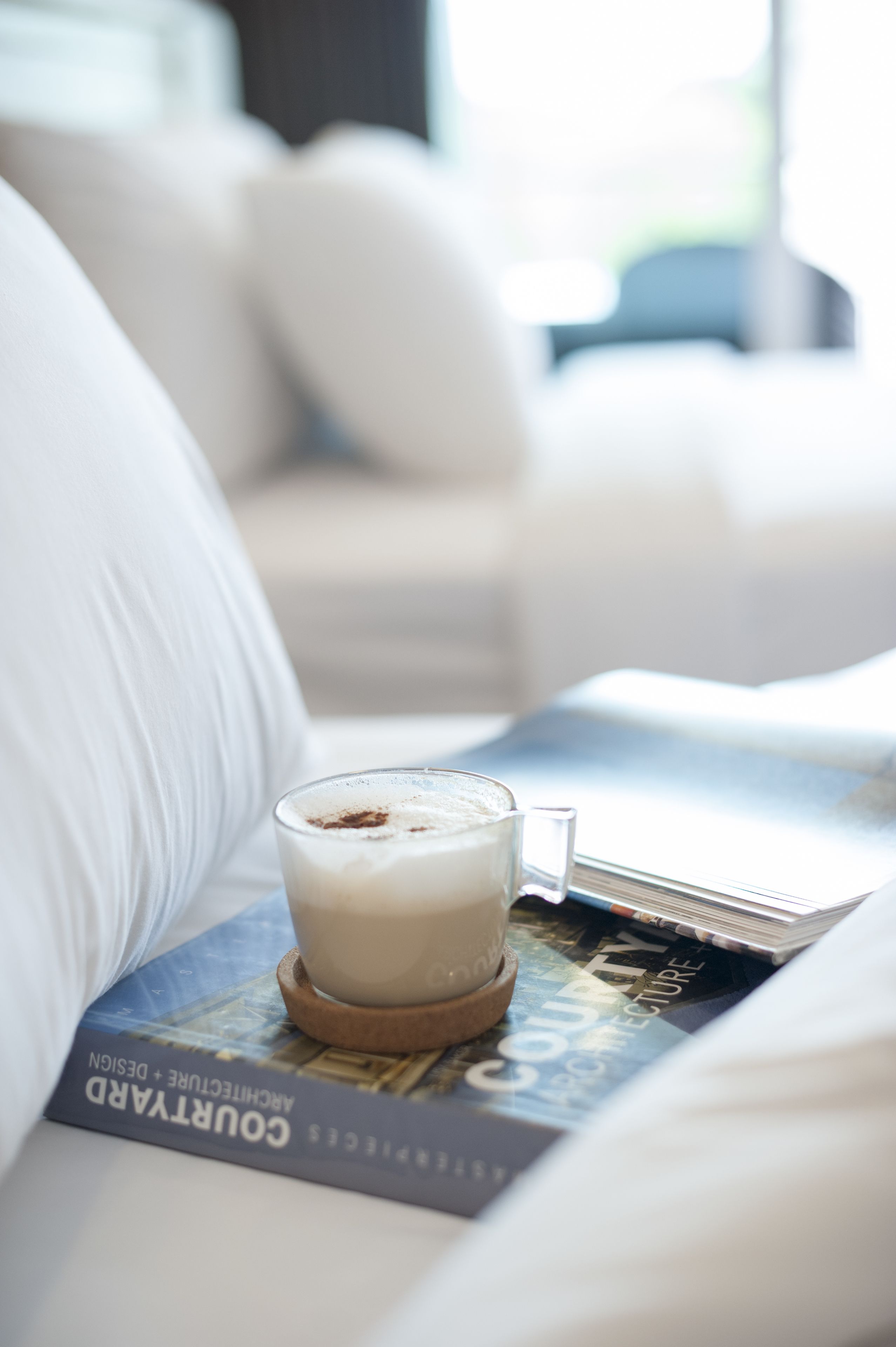 A book titled "COURTYARD ARCHITECTURE + DESIGN" on a white couch with a glass of milk.