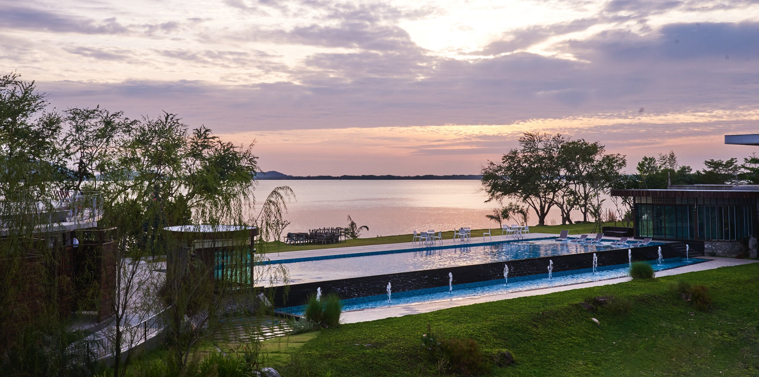 A pool area with a view of a lake, surrounded by trees and modern architecture.