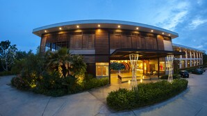 A modern hotel with a curved facade, large windows, and a well-lit entrance. - Baan Rim Ao (Chanthaburi)
