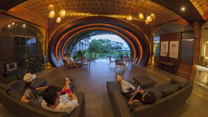 A spacious indoor area with a circular wooden ceiling, comfortable seating, and a view of the outdoors. - Baan Rim Ao (Chanthaburi)