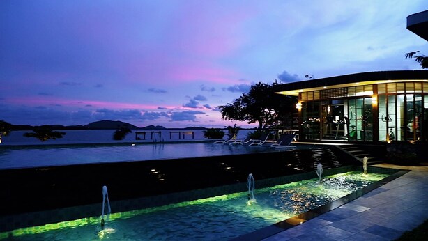 A swimming pool with a water feature, a covered seating area, and a view of the water. - Baan Rim Ao (Chanthaburi)