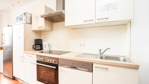 Uma cozinha moderna com armários brancos, eletrodomésticos de aço inoxidável, lava-louças e máquina de café.